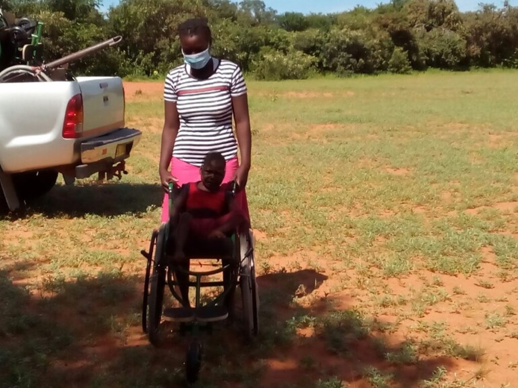 Photo of Loveness with her Child seated in a wheelchair in front of her